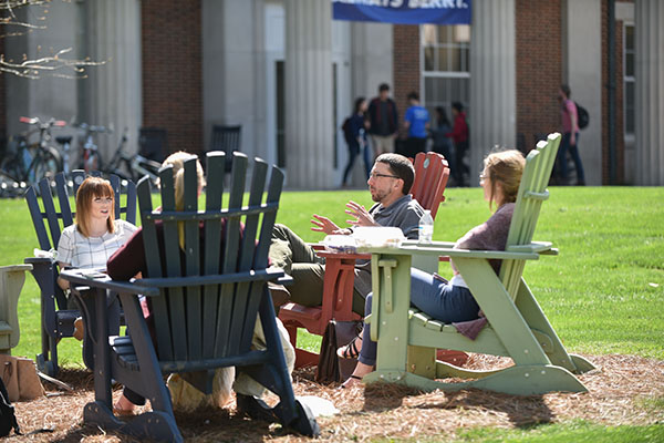 students and professor sitting outside in a circle