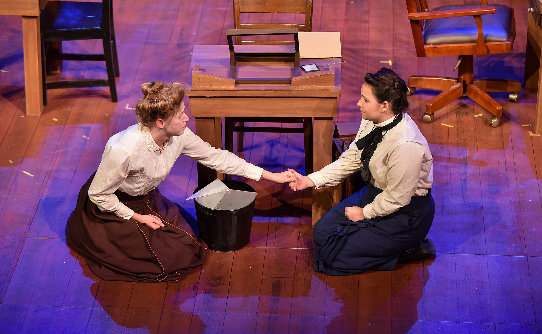 Two female students holding hands on a stage