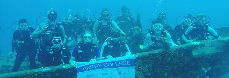 Students underwater with sunken ship