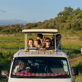 group of students looking out the of a car while ona safari