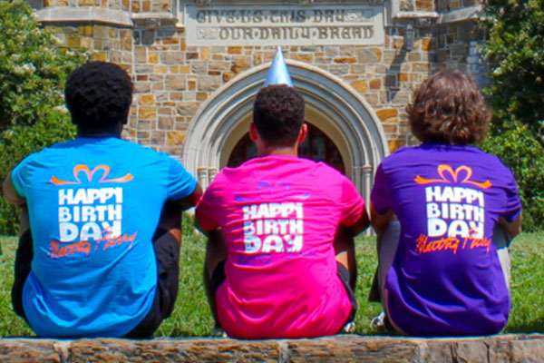 students sitting on a wall wearing Happy Birthday shirts