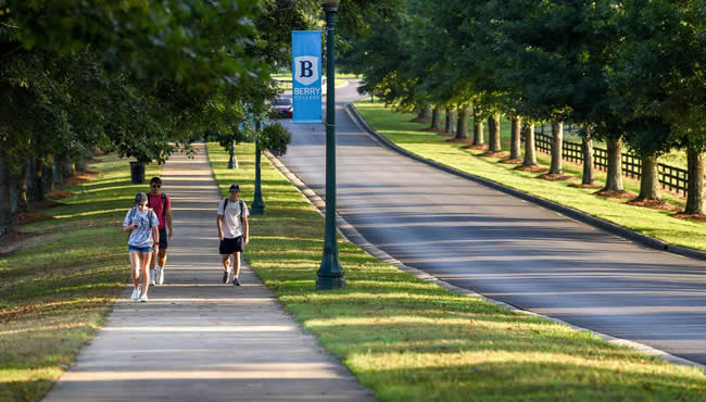 three students walking on a sidewalk on campus