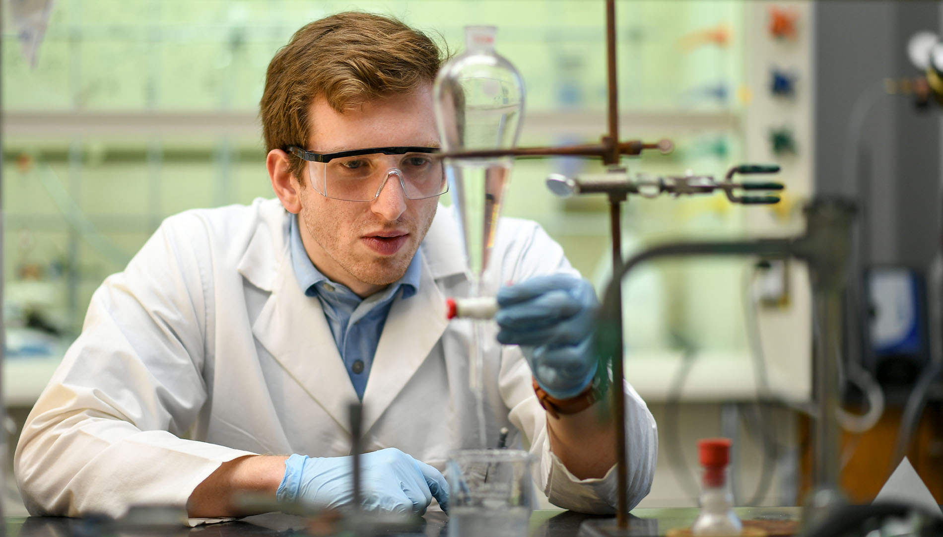 a male student measuring liquids and working in a laboratory