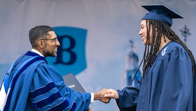 Berry College President Sandeep Mazumder shakes hands with a graduating female on stage