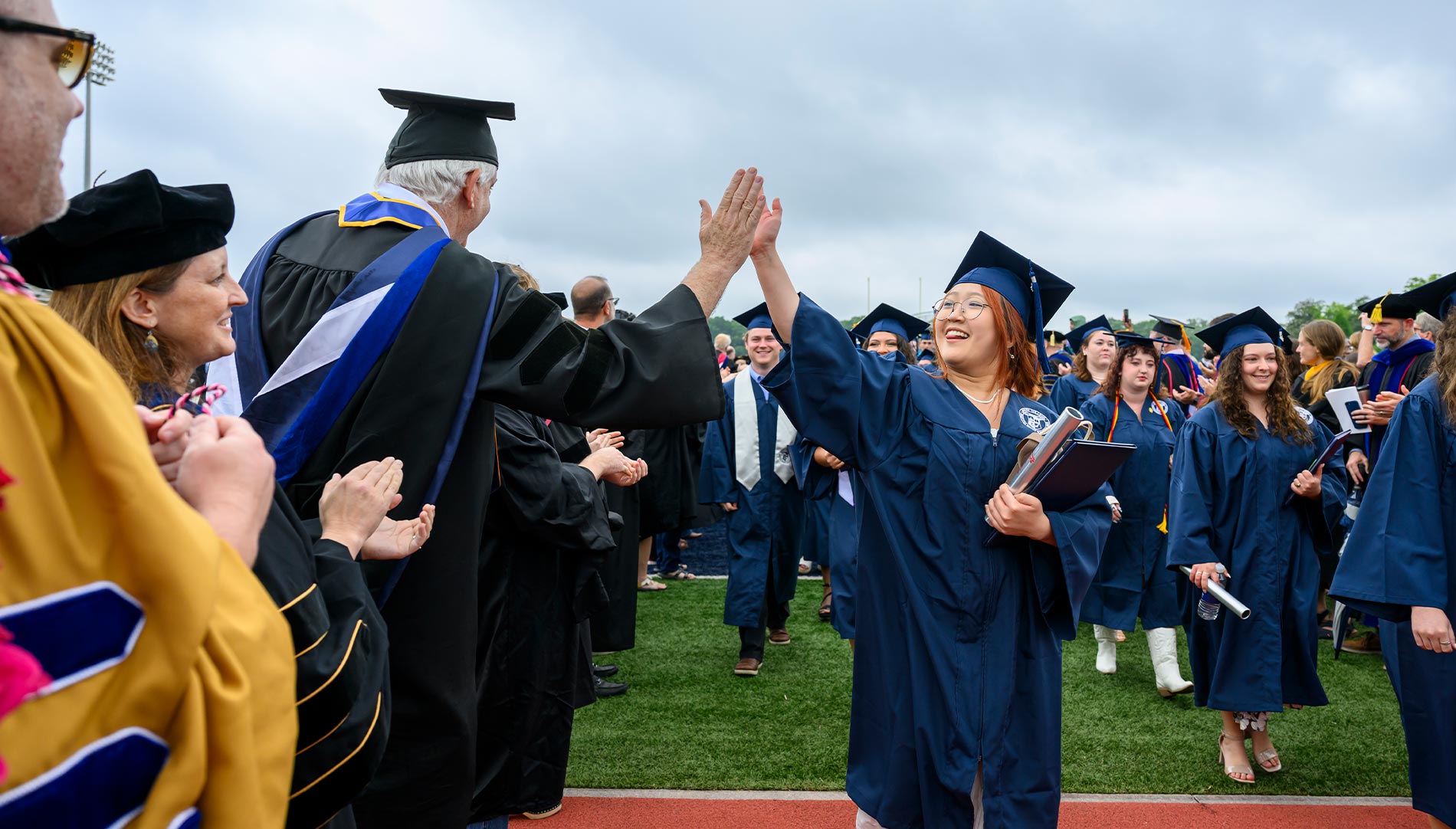 A professor and female student high five during graduation