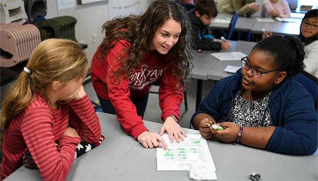 People around a table helping each other with work