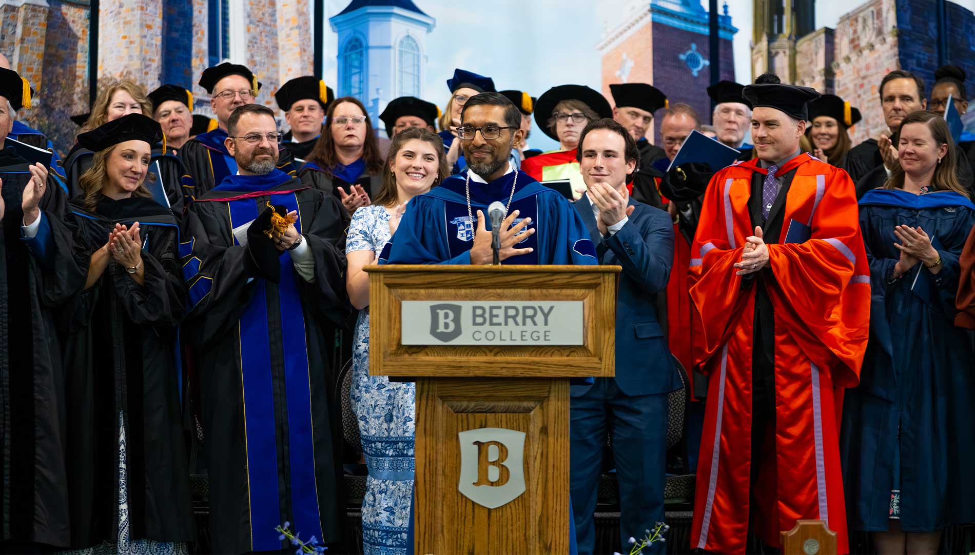 President Sandeep Mazumder with his hand over his chest as he smiles behind a podium
