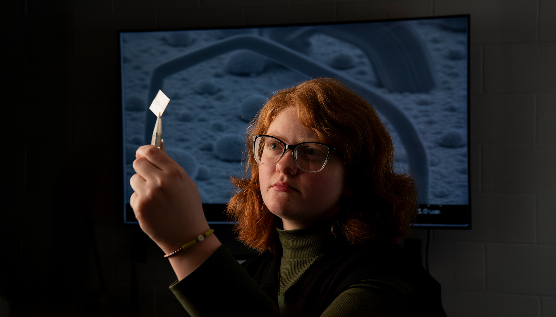 Madison Pierce, physics major, inspecting a piece of paper with tweezers