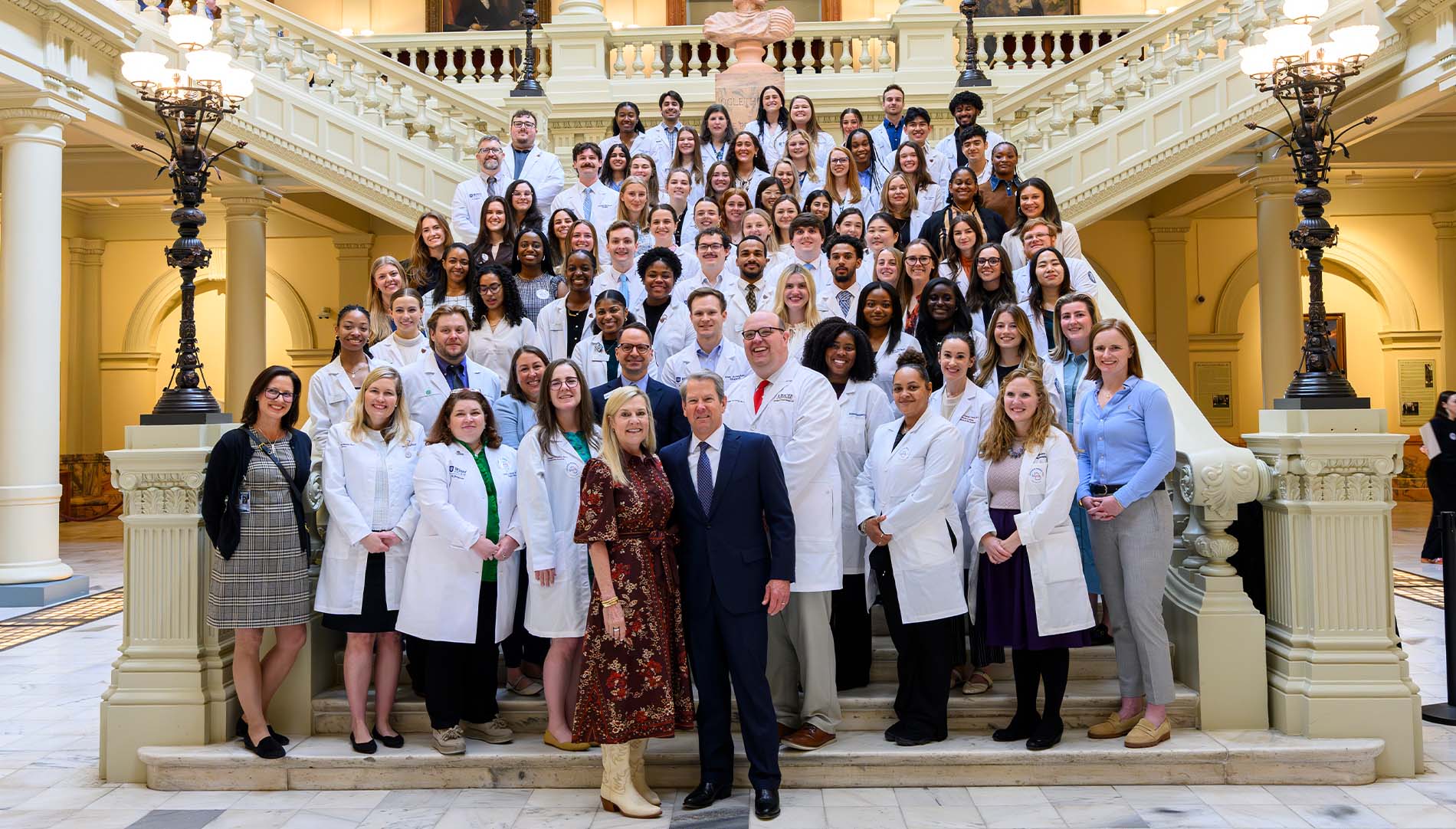 They Berry College Physician Associate Program students and faculty in white lab coats on the steps of the Capitol with the Governor and First Lady