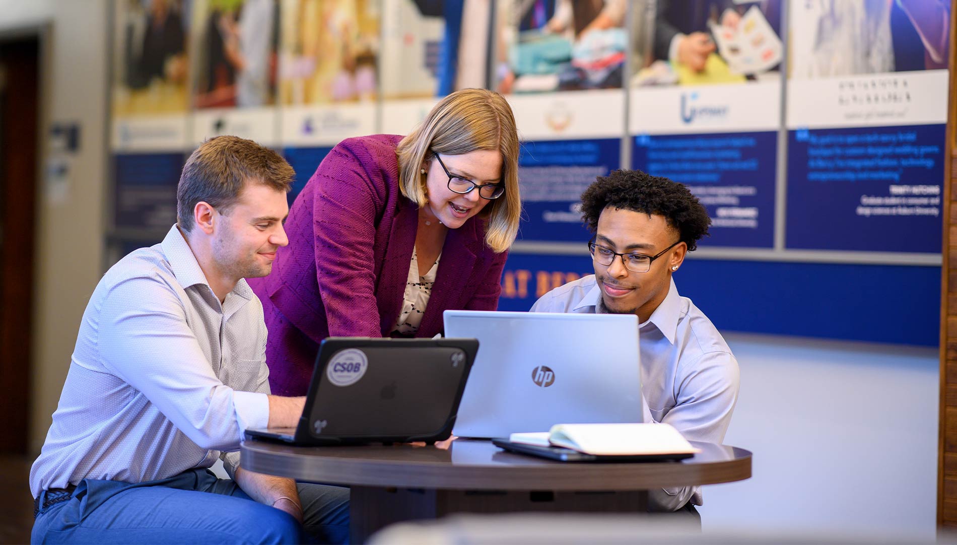 Female professor and two male students looking at a computer screen