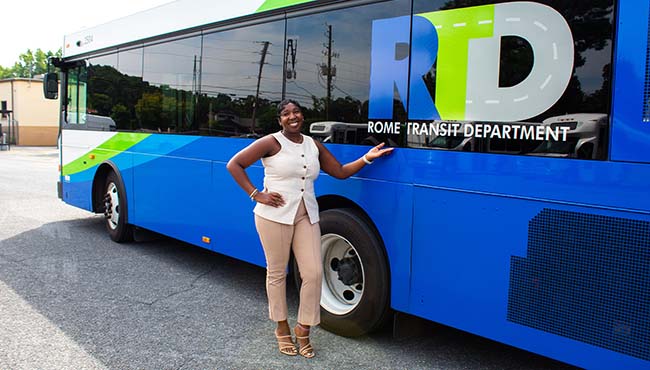 Courtnay Griffin smiling while standing next to a Rome Transit Department bus