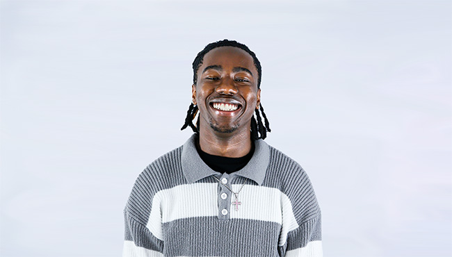 Nile King smiling in front of a light gray background