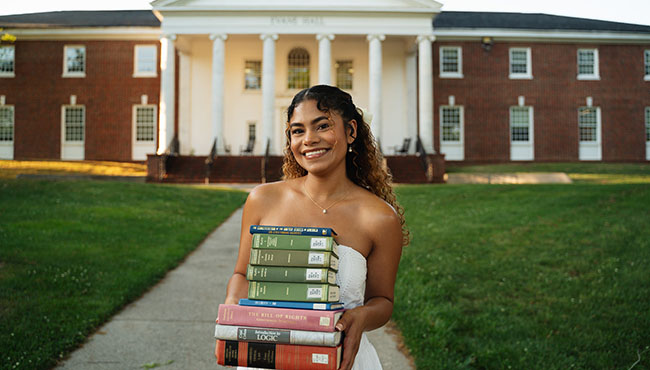 Yinia Hernandez smiling and holding a stack of law books