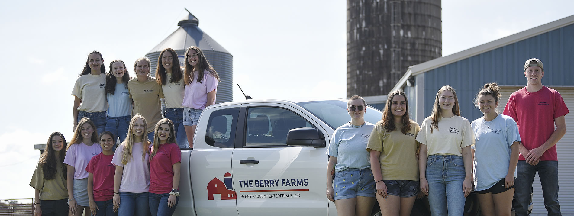 A group of Berry Farms team members stand in and around the Berry Farms truck at the Blue Tech Barn