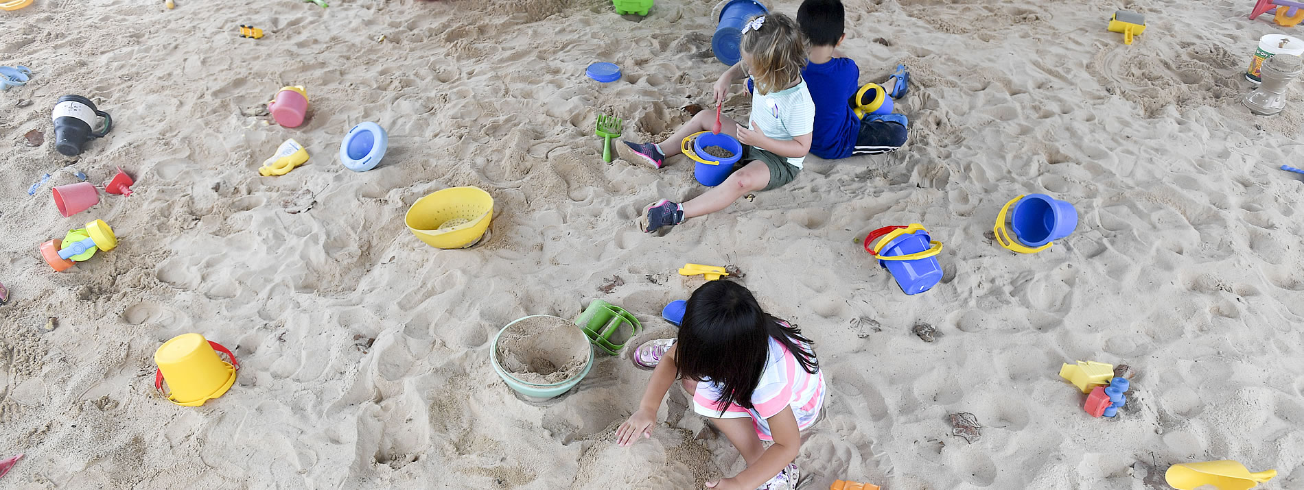 three young children playing in a sandbox